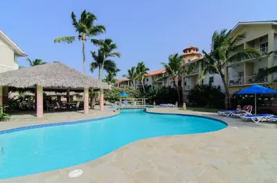 a swimming pool at a resort with palm trees at Ocean Dream top floor Studio with balcony in Cabarete