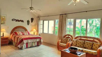 a bedroom with a bed and a chair and windows at Ocean Dream Studios Cabarete in Cabarete