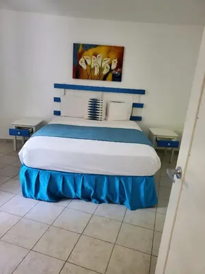 a bedroom with a bed with blue and white pillows at Costarena Beach Hotel in Las Terrenas