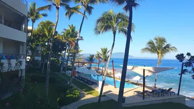 a resort with a pool and palm trees and the ocean at Infiniti Blu Luxury Ocean Front Condos in Sosúa