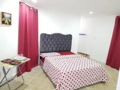 a bedroom with a bed with red curtains and a table at Wilkan Hotel in Las Terrenas