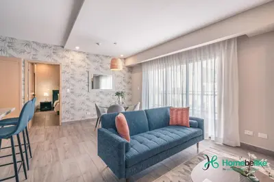 a living room with a blue couch and a table at Chic Fully Serviced Apartment at Regatta Living II - 705 in Los Prados