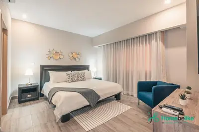 a bedroom with a bed and a blue chair at Chic Fully Serviced Apartment at Regatta Living II - 705 in Los Prados