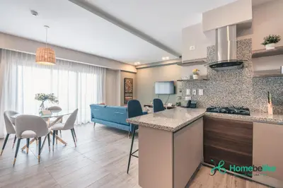 a kitchen and living room with a table and chairs at Chic Fully Serviced Apartment at Regatta Living II - 705 in Los Prados