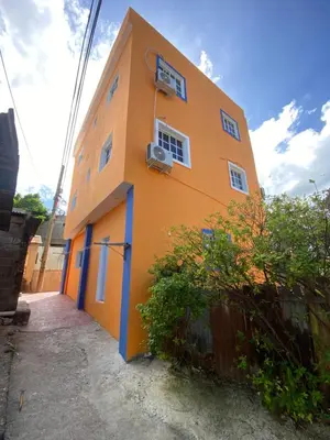 a orange building with a fence in front of it at RESIDENCIAL DOÑA GLORIA in San Felipe de Puerto Plata