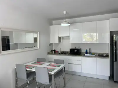 a kitchen with white cabinets and a table and chairs at Sunny garden in La Laguna