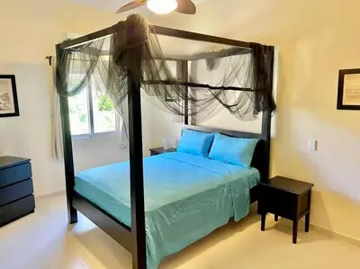a bedroom with a canopy bed with blue pillows at The Cove Apartment Second Floor 5C in Santa Bárbara de Samaná