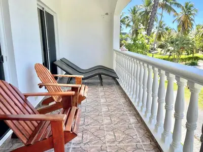 a porch with two chairs and a balcony with palm trees at The Cove Apartment Second Floor 5C in Santa Bárbara de Samaná