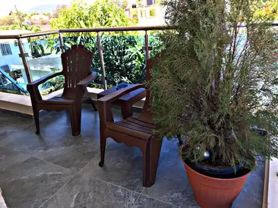 two chairs sitting on a balcony with plants at Fully Equipped New 2br Apt-dt2mins To The Beach in Sosúa