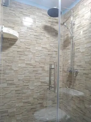 a shower in a bathroom with a stone wall at Paulino in Santiago de los Caballeros