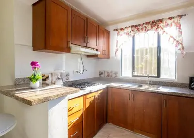 a kitchen with wooden cabinets and a window at Fully Equipped 2br Apt-dt5mins To The Beach in Sosúa
