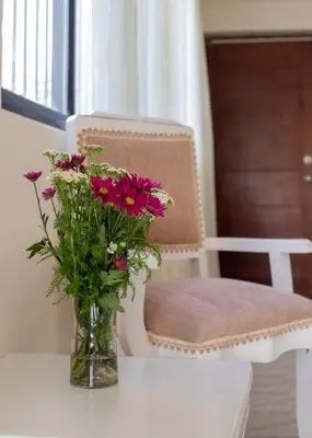 a vase with flowers on a table next to a chair at Fully Equipped 2br Apt-dt5mins To The Beach in Sosúa