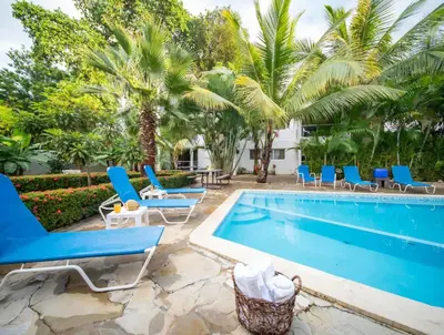 a pool with blue chairs and palm trees at Fully Equipped 2br Apt-dt5mins To The Beach in Sosúa
