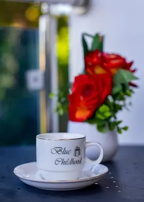 a coffee cup sitting on a table with a vase of roses at Cozy and Central apartment 1br-1ba with Pool in Sosúa