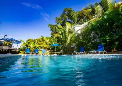 a swimming pool with blue chairs and umbrellas at Cozy and Central apartment 1br-1ba with Pool in Sosúa