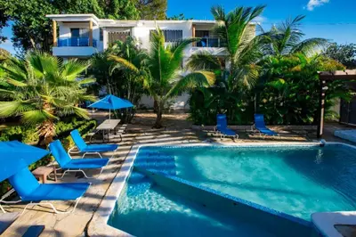 a swimming pool with chairs and a house at Cozy and Central apartment 1br-1ba with Pool in Sosúa