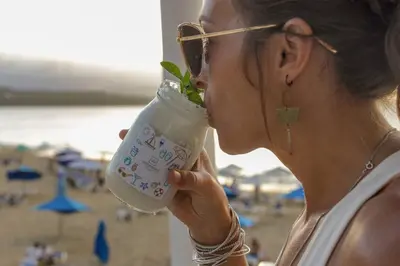a woman drinking a drink at the beach at Room #26 at Waterfront Playa Alicia in Sosúa