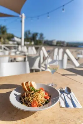 a plate of pasta on a table with a glass of wine at Room #26 at Waterfront Playa Alicia in Sosúa