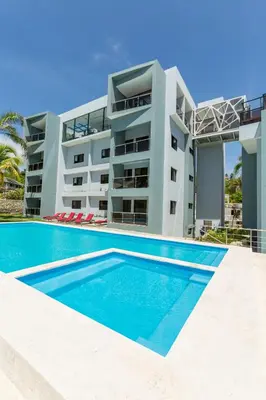 a villa with a swimming pool in front of a building at Skylight Suites Hotel in San Felipe de Puerto Plata