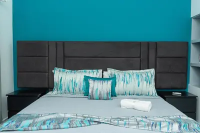 a bed with a blue head board and pillows at Skylight Suites Hotel in San Felipe de Puerto Plata