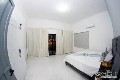 a white bedroom with a bed and a window at Skylight Suites Hotel in San Felipe de Puerto Plata