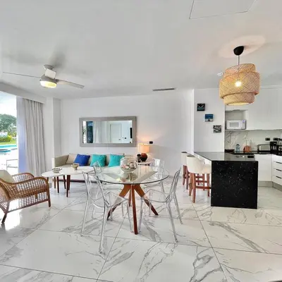 a living room and kitchen with a glass table and chairs at Hermoso Apartamento Cana Rock Star Acceso Directo a la Piscina C-105, C-106, B-102 y B-104 in Punta Cana