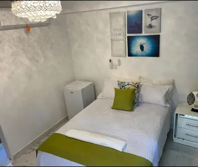 a small bedroom with a bed with green pillows at Central Area Bedroom With Common Kitchen, living room in Sosúa