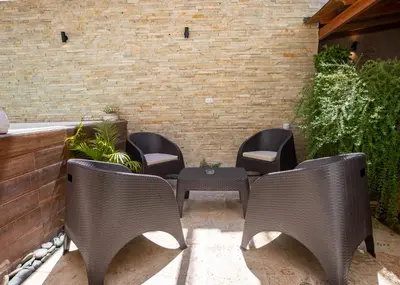 a patio with chairs and a table and a brick wall at Cozy 1bd with common Jacuzzi in Sosúa