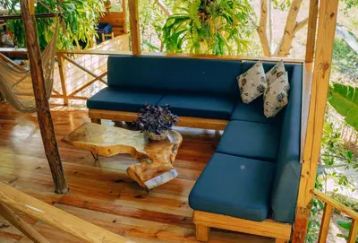 a blue couch and a table on a porch at EL GALLO ECOLODGE in San Felipe de Puerto Plata