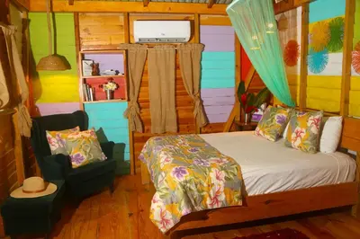 a bedroom with a bed and a chair in it at EL GALLO ECOLODGE in San Felipe de Puerto Plata