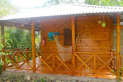a wooden cabin with a hammock in it at EL GALLO ECOLODGE in San Felipe de Puerto Plata