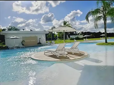 a pool with two chairs and an umbrella in the water at Cana Rock Star, Vista al campo de golf y Piscina C-303, B-400, B-506 y B-502 - Desayuno in Punta Cana