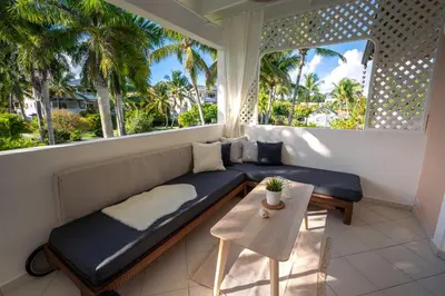 a balcony with a couch and a table and palm trees at Family Dominicus Apartment - Bayahibe in Bayahibe