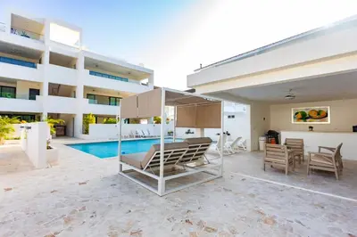 a patio with chairs and a pool in front of a building at Stella Aparthotel, Las Terrenas in Las Terrenas