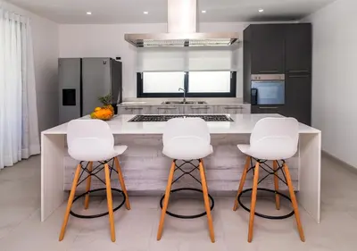 a kitchen with a counter with four white bar stools at Stella Aparthotel, Las Terrenas in Las Terrenas