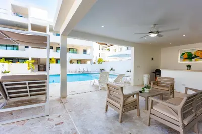 a living room with a table and chairs and a pool at Stella Aparthotel, Las Terrenas in Las Terrenas