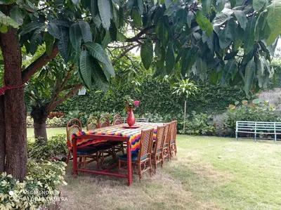 a table with chairs and a vase on top of it at Paraiso Hortensia Ecolodge in Santiago de los Caballeros