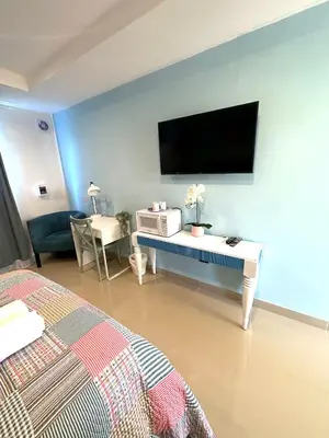 a bedroom with a bed and a desk with a tv on the wall at Noe Hotel , One Bed Room Close to The beach Room #1 in Punta Cana