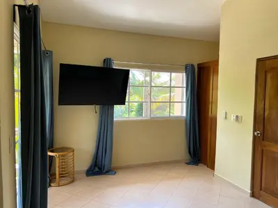 a living room with a flat screen tv and a window at Villa 102A, 5 master bedroom and 5 full bathrooms with private pool in Sosúa