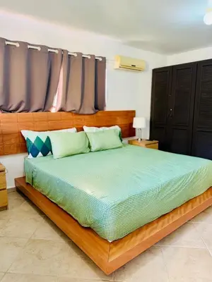 a bedroom with a large wooden bed with green pillows at Hispaniola 3 bed, 3 bath Villa with pool & jacuzzi in Sosúa