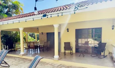 a house with a patio with chairs and a table at Hispaniola 3 bed, 3 bath Villa with pool & jacuzzi in Sosúa