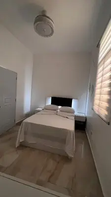 a white bedroom with a bed and a window at Hotel Unico in Santo Domingo