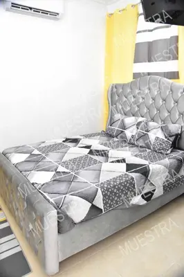 a bed with a black and white quilt on it at Apartamento en la carreras próximo al monumento in Santiago de los Caballeros