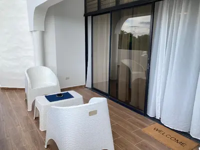 a balcony with white chairs and a table and a window at Flat Anchor Marine Monte Vista in Sosúa