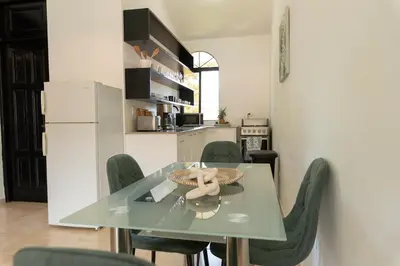 a dining room with a glass table and green chairs at Flat Anchor Marine Monte Vista in Sosúa