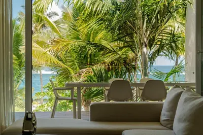 a living room with a table and chairs and palm trees at Ultravioleta Boutique Residences in Cabarete