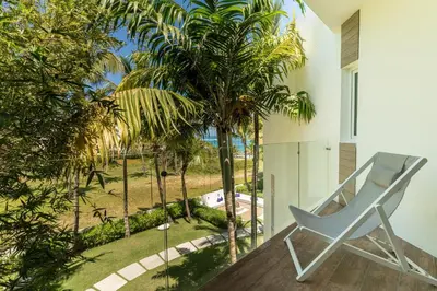 a chair on a balcony with palm trees at Ultravioleta Boutique Residences in Cabarete