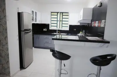 a kitchen with a refrigerator and two bar stools at Casa familiar in San Pedro de Macorís