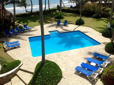a swimming pool with lounge chairs and a beach at La Punta Apartamentos in Cabarete