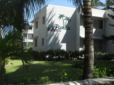 a building with a palm tree in front of it at La Punta Apartamentos in Cabarete